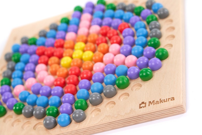 Kugelbrettspiel: Nahaufnahme eines Makura Steckspiels mit bunten Kugeln, die ein abstraktes Muster formen, mit sichtbarem Markenlogo im Holz